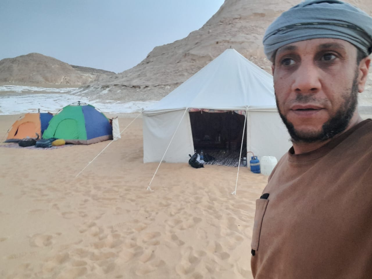 Yasser in a Bedouin headscarf in front of the camp tents